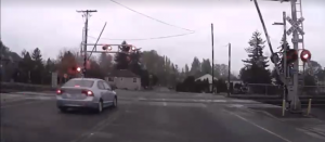 still from dashcam video showing car driving thru rr crossing while arms are transitioning and signals activated 2015