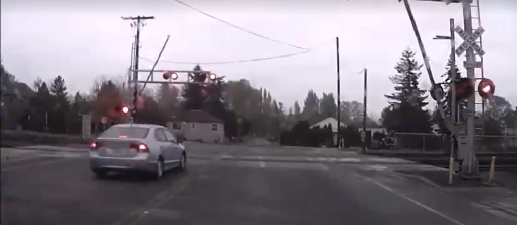 still from dashcam video showing car driving thru rr crossing while arms are transitioning and signals activated 2015
