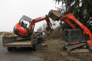 A compact front loader was used to try and return a toppled compact excavator to its trailer after it collided with the bnsf bridge over main street 2018-02-21