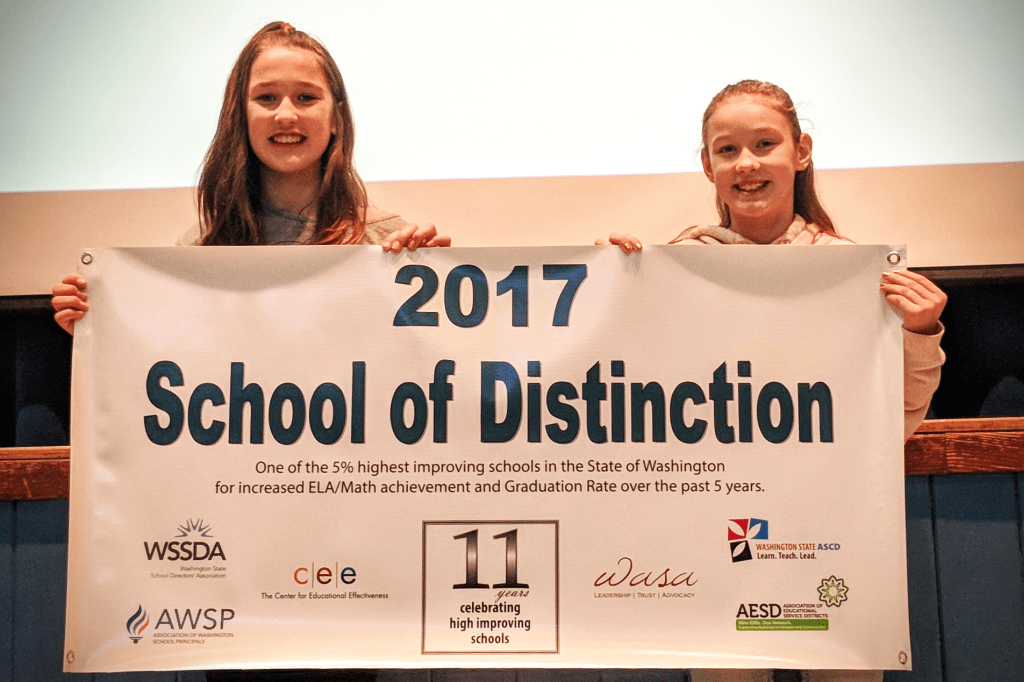 l-r 5th grade Leadership Award winners Kaelin and Cammy hold Central Elementary's 2017 school of distinction award banner 2017-12