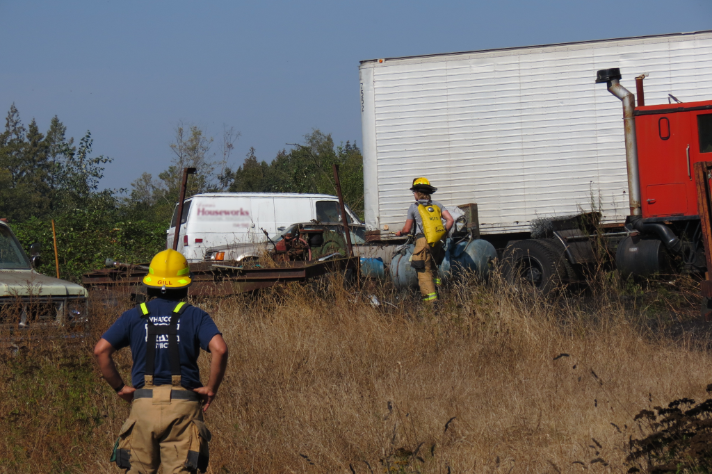 A WCFD7 firefighter can be seen with a yellow water pack on their back to get water onto a grass fire on Paradise Road 2018-09-05