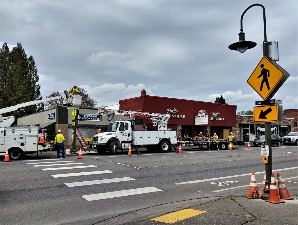 Puget Sound Energy contractor installs 1 of 2 rectangular rapid flash beacons (RRFB) mounted on light poles at 1st Avenue and Main Street (April 24, 2020). Photo: My Ferndale News