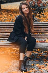 woman wearing black blazer sitting on wooden bench