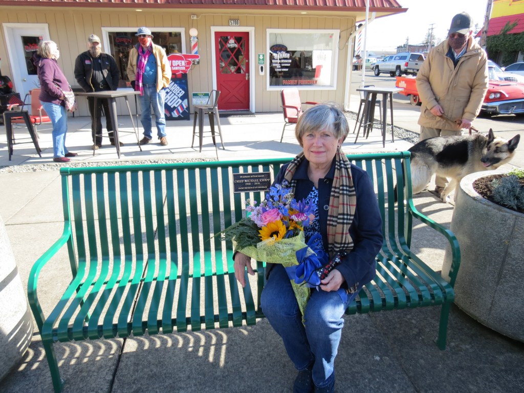 Nancy Knapp poses sitting on a bench dedicated to the memory of her husband, former Ferndale Chief of Police Michael Knapp (February 26, 2021). Photo: My Ferndale News