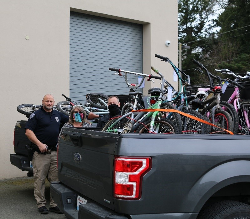 Ferndale Police Officer Eric Grant, Supervisor Kim Martin and Lieutenant Matt Huffman pose outside the Ferndale Police Station with bikes loaded to be donated. Photo: City of Ferndale