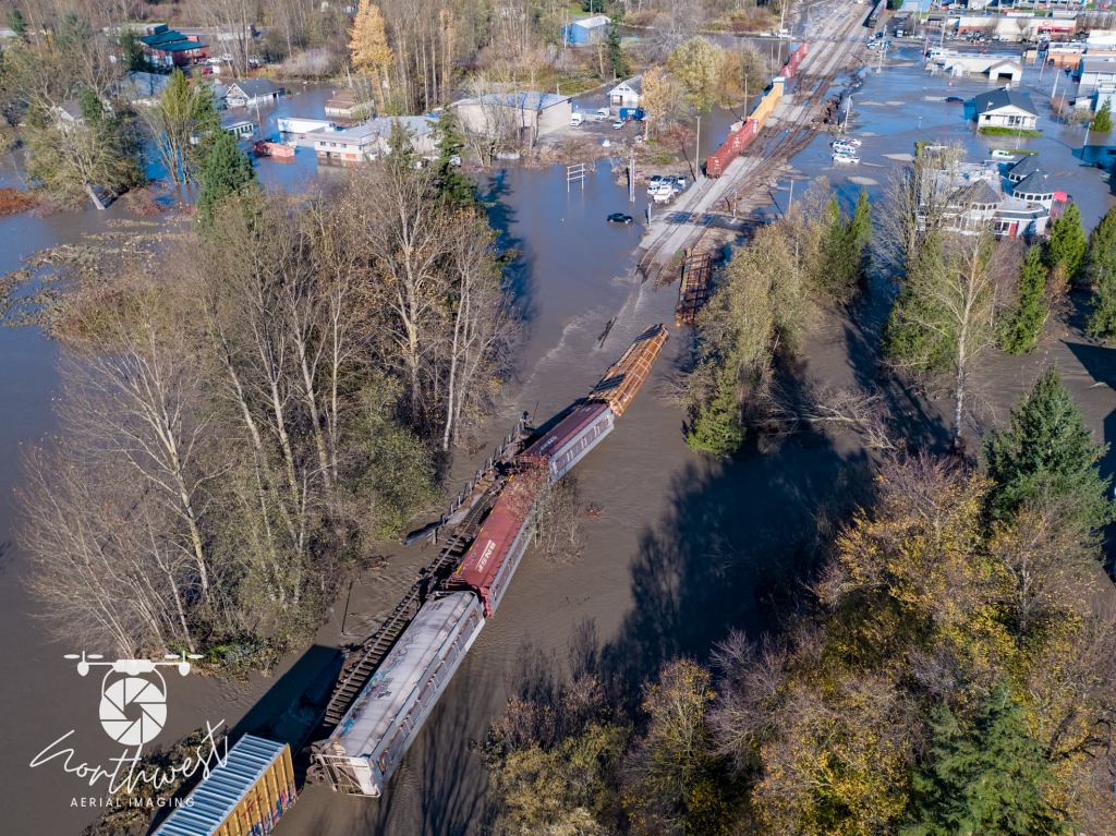 Train cars are seen laying alongside tracks that were undermined by floodwaters (November 16, 2021). Photo used with permission from Northwest Aerial Imaging